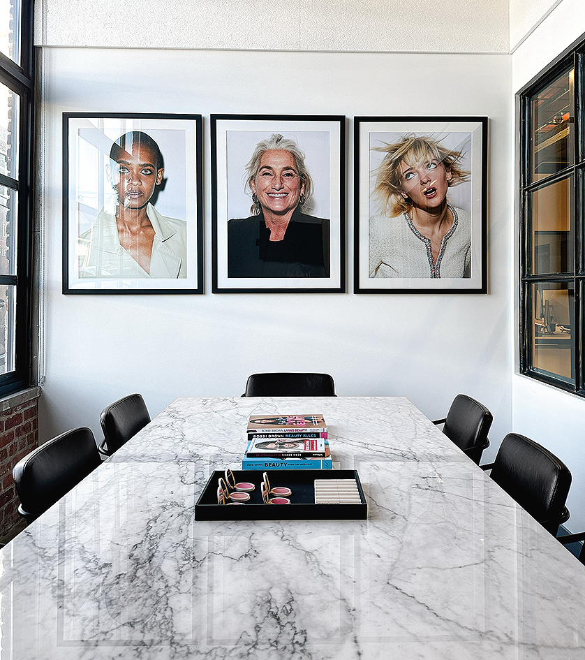 Conference room featuring posters of three models, a marble-topped Parsons table and Mazie chairs.