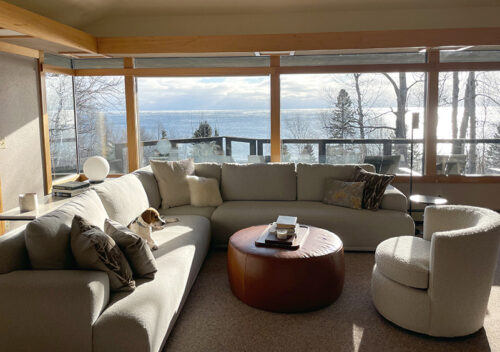 Living room furniture in sunlit cabin looking over Lake Superior