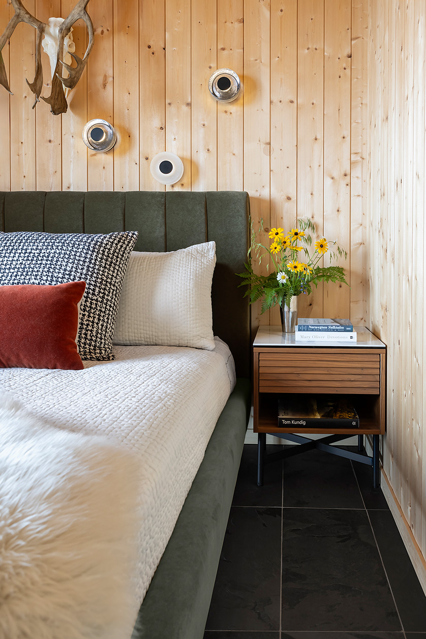 Bedroom with green velvet bed and walnut nightstand with ceramic top.